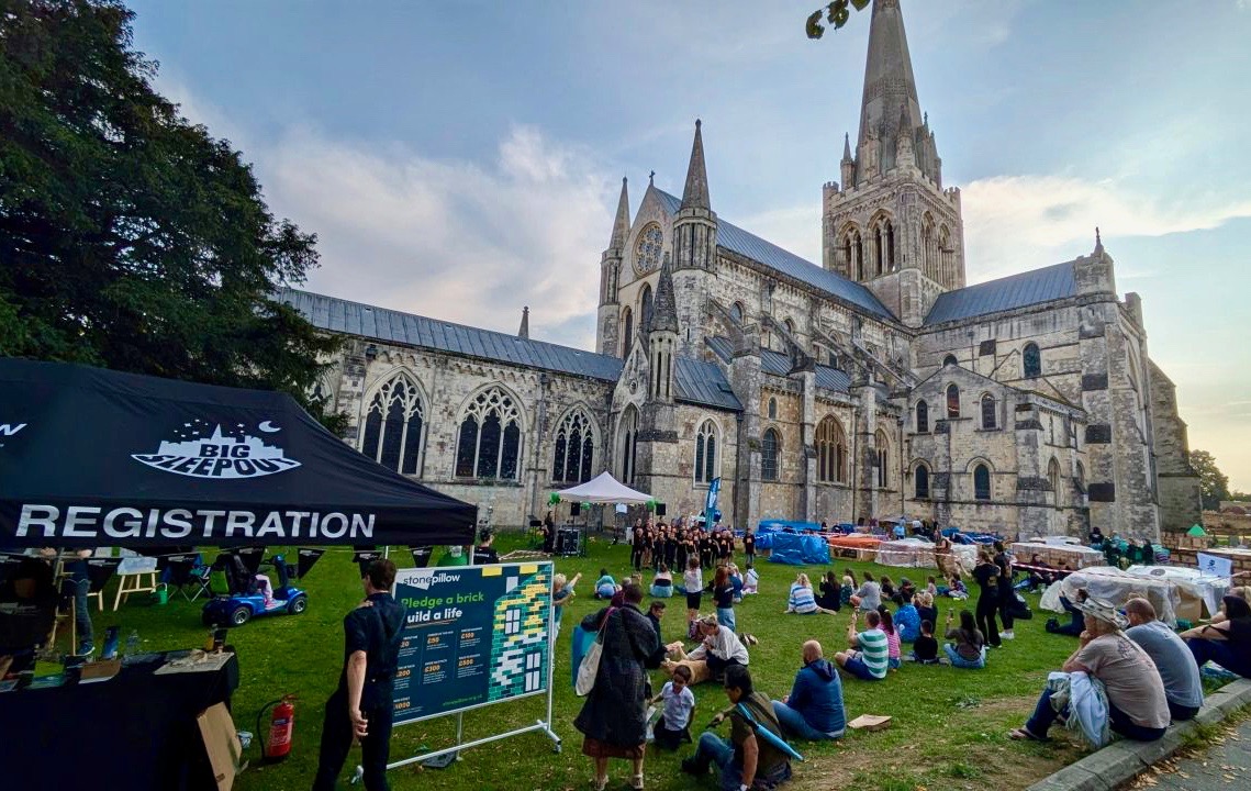 Chichester Cathedral in the background with the green in the foreground and people attending the BIG Sleep Out event